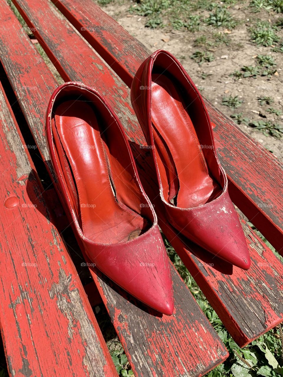 red shoes, symbol of the world day against violence against women, resting on a red bench