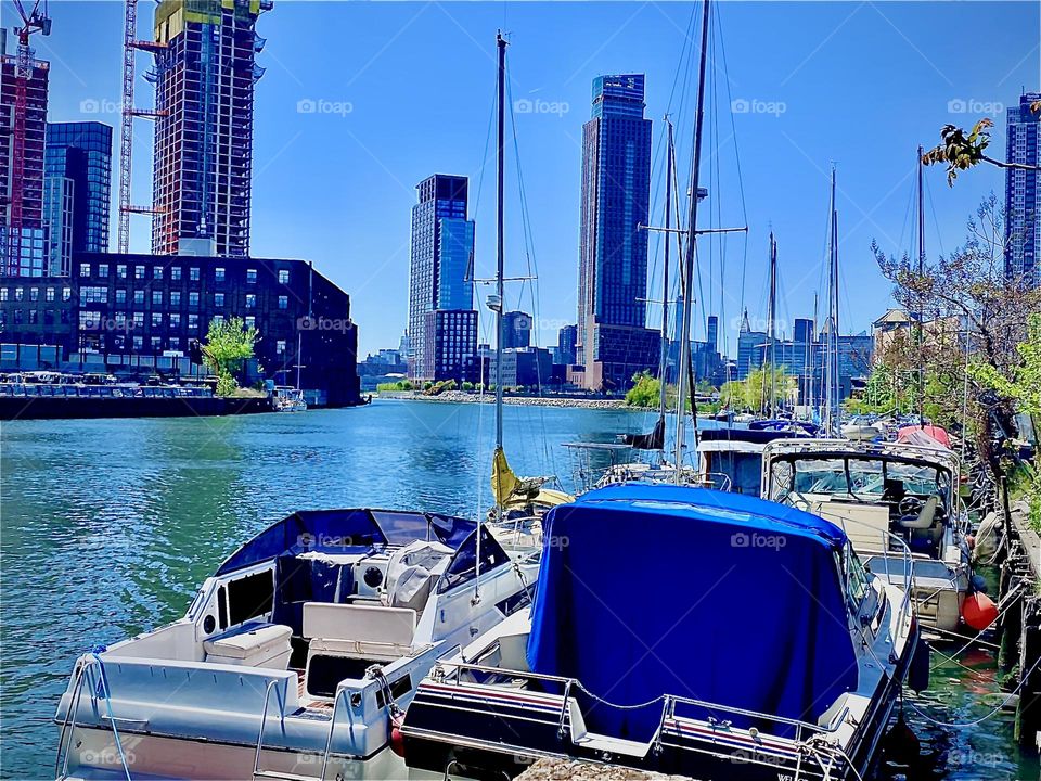 A bit more close up to the boats in the creek this view from the parking lot beneath the „Pulaski Bridge“ shows altogether three boroughs of the city of New York, Brooklyn, Queens and parts of Manhattan in the far distance. 2022. Hypnotic Production