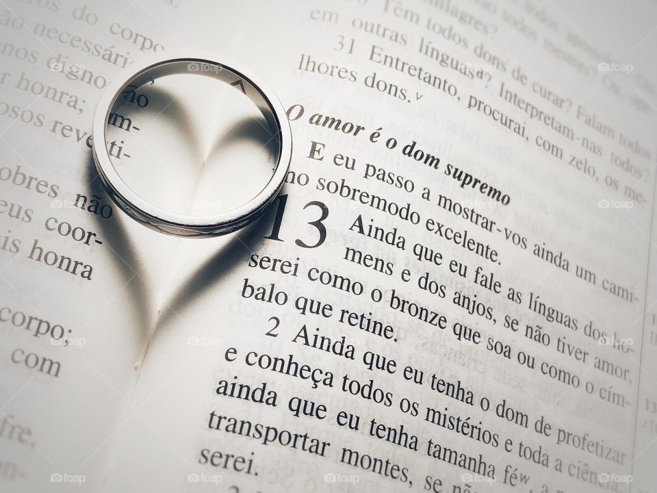 Love. The ring’ shadow creates a beautiful heart on top of the Bible text of Love (in Portuguese)