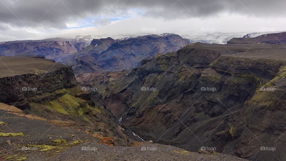 Holiday in Iceland hiking the Laugavegur long distance trail during summertime. Great view of river, glacier  & summits with grass, gravel, rocks, snow, ice. Amazing mountain adventure