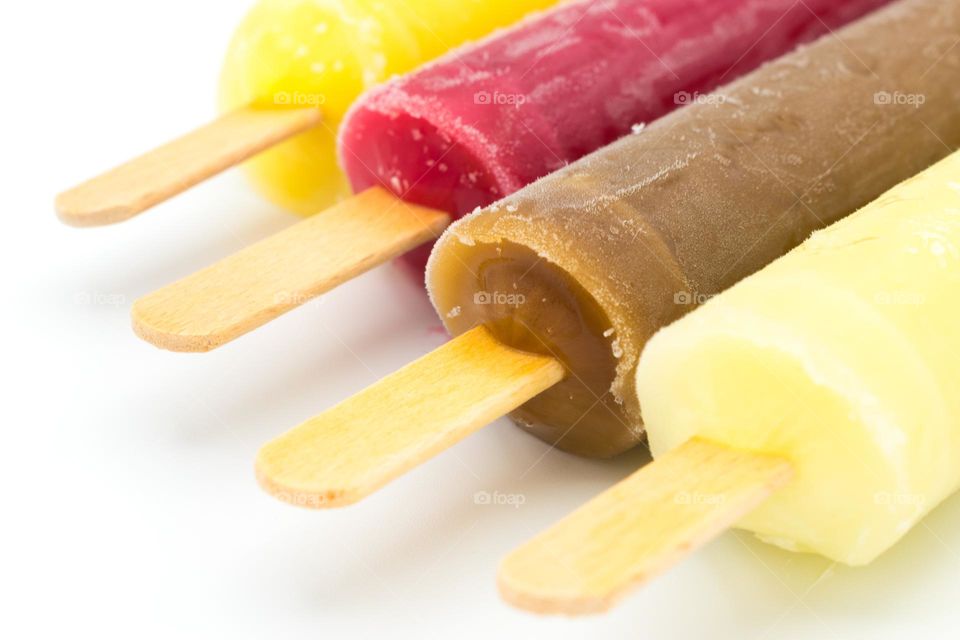 Close-up image of an assortment of ice lollies (popsicles) of different flavours. Wooden sticks. Isolated on a white background