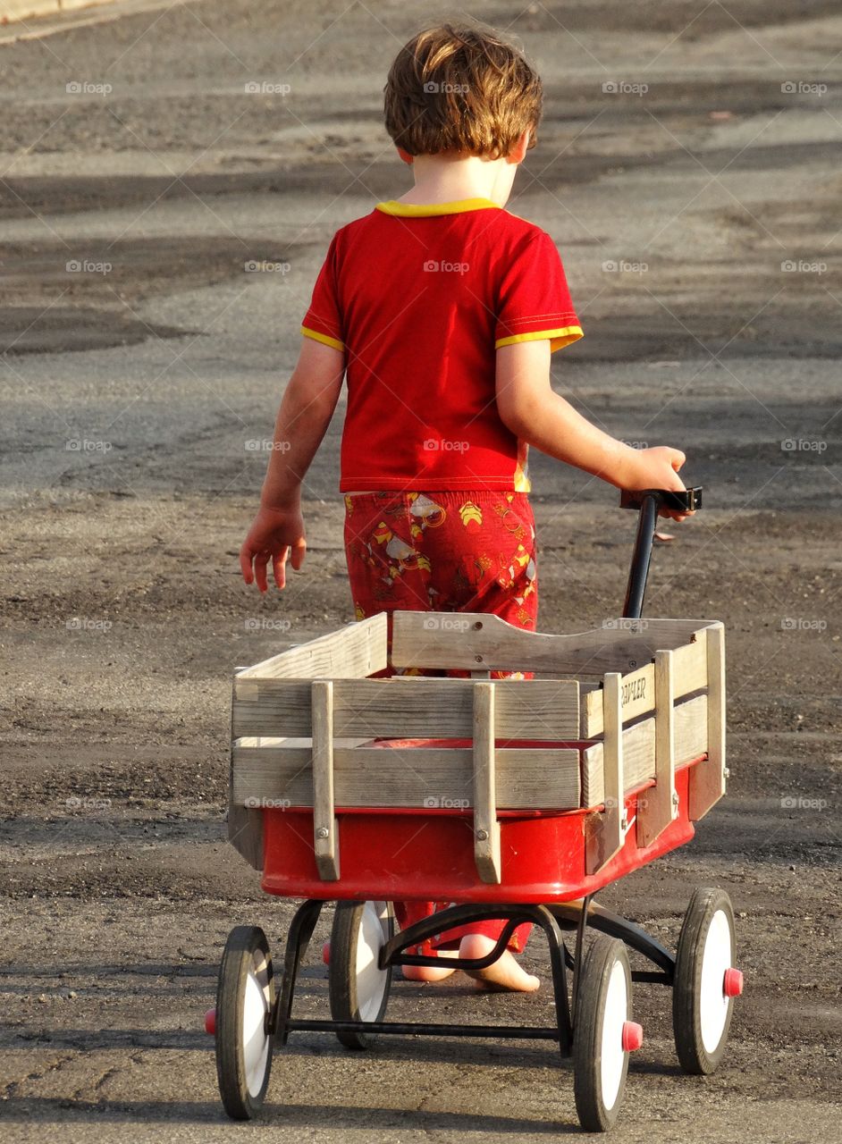 Little Boy With Red Wagon. Young Boy Pulling His Wagon In The Golden Hour
