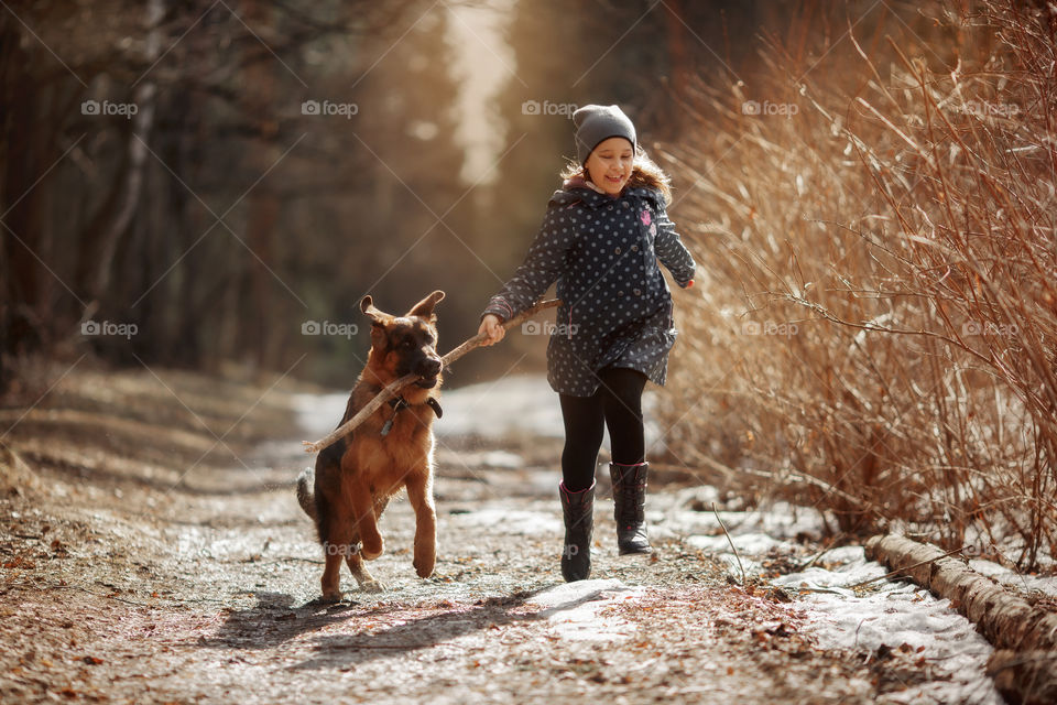 Girl walking with German shepherd puppy in a spring forest 