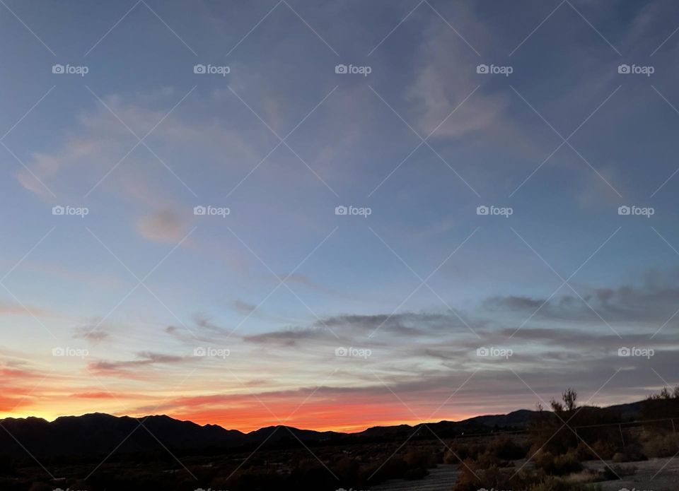 A colorful sunset with mountains and clouds. 