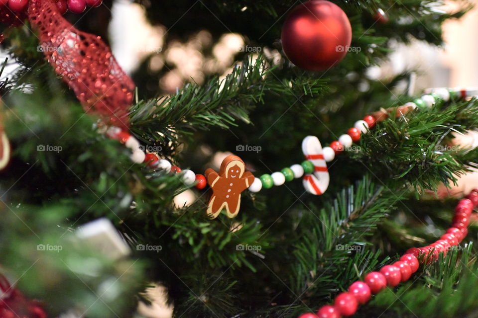 Gingerbread man, candy cane and other ornaments on Christmas tree.