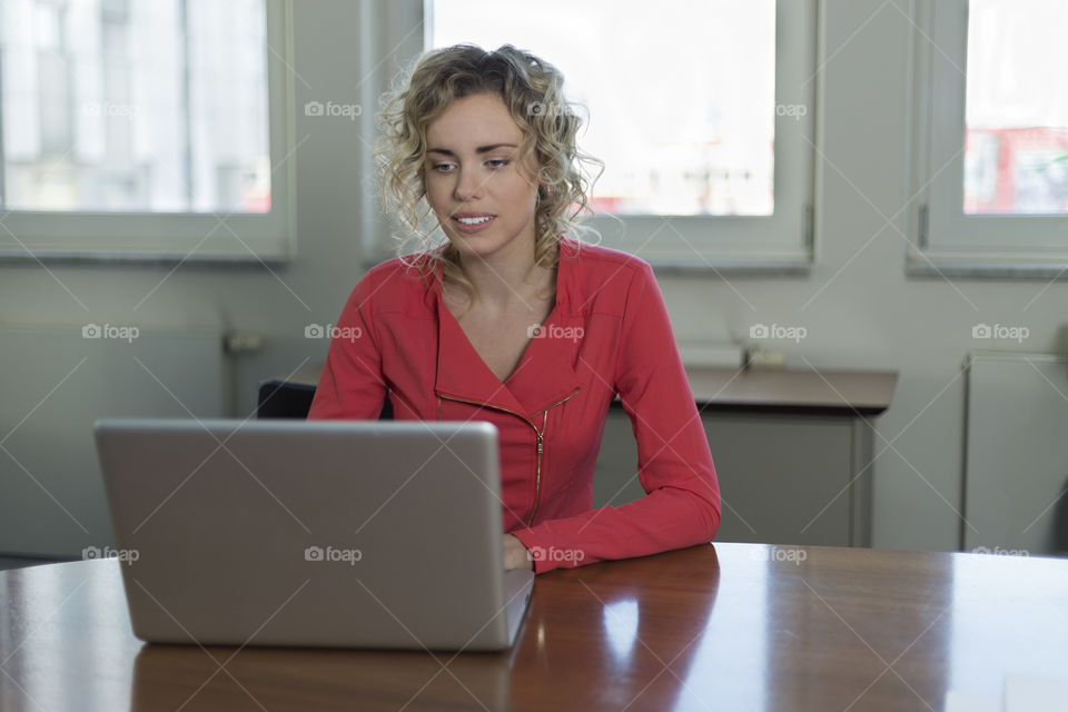 Young blonde woman using laptop in office