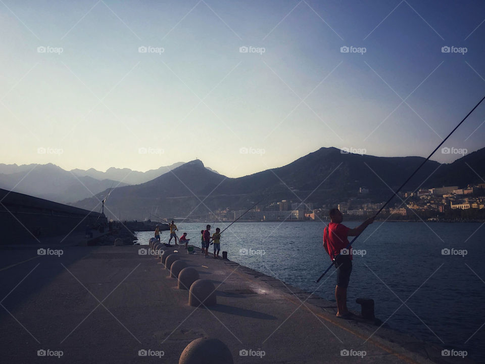 Fisherman and children fishing off a pier in Salerno, Italy