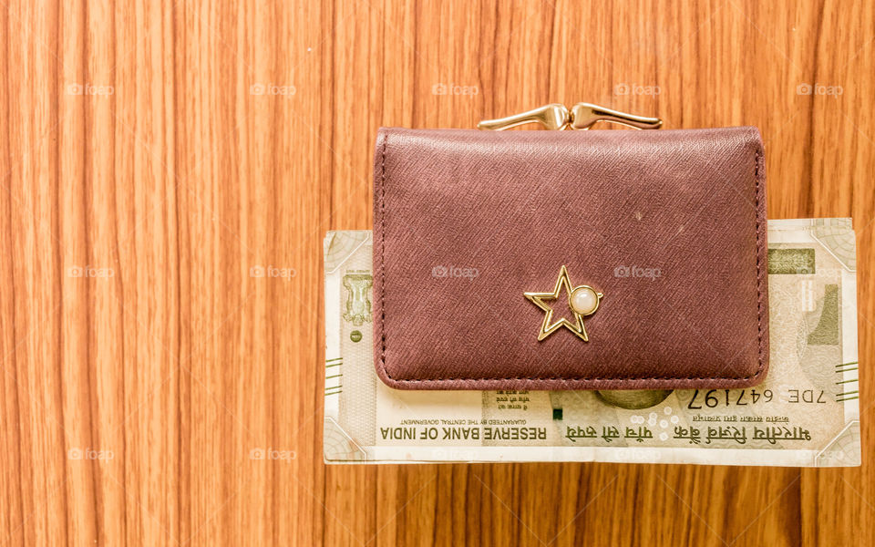 Indian five hundred (500) rupee cash note in brown color wallet leather purse on a wooden table. Business finance economy concept. High angel view with copy space room for text on left side of image.