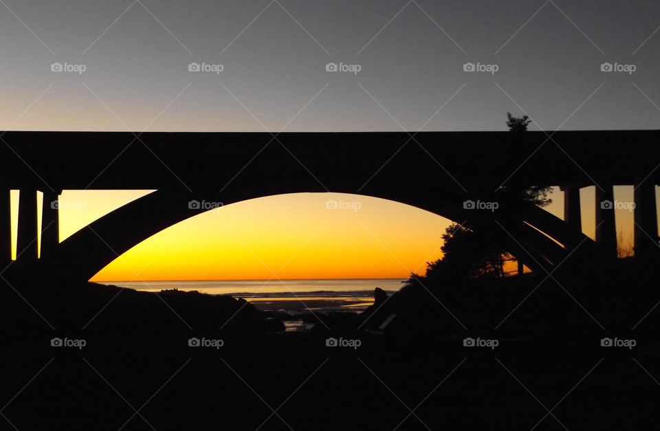 Silhouette of bridge over the sea during sunset