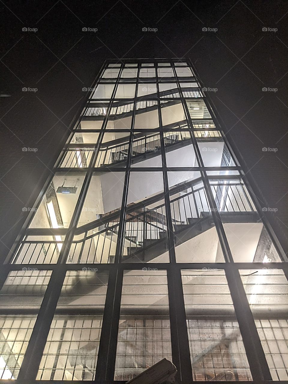 angled view of an illuminated staircase  through glass.