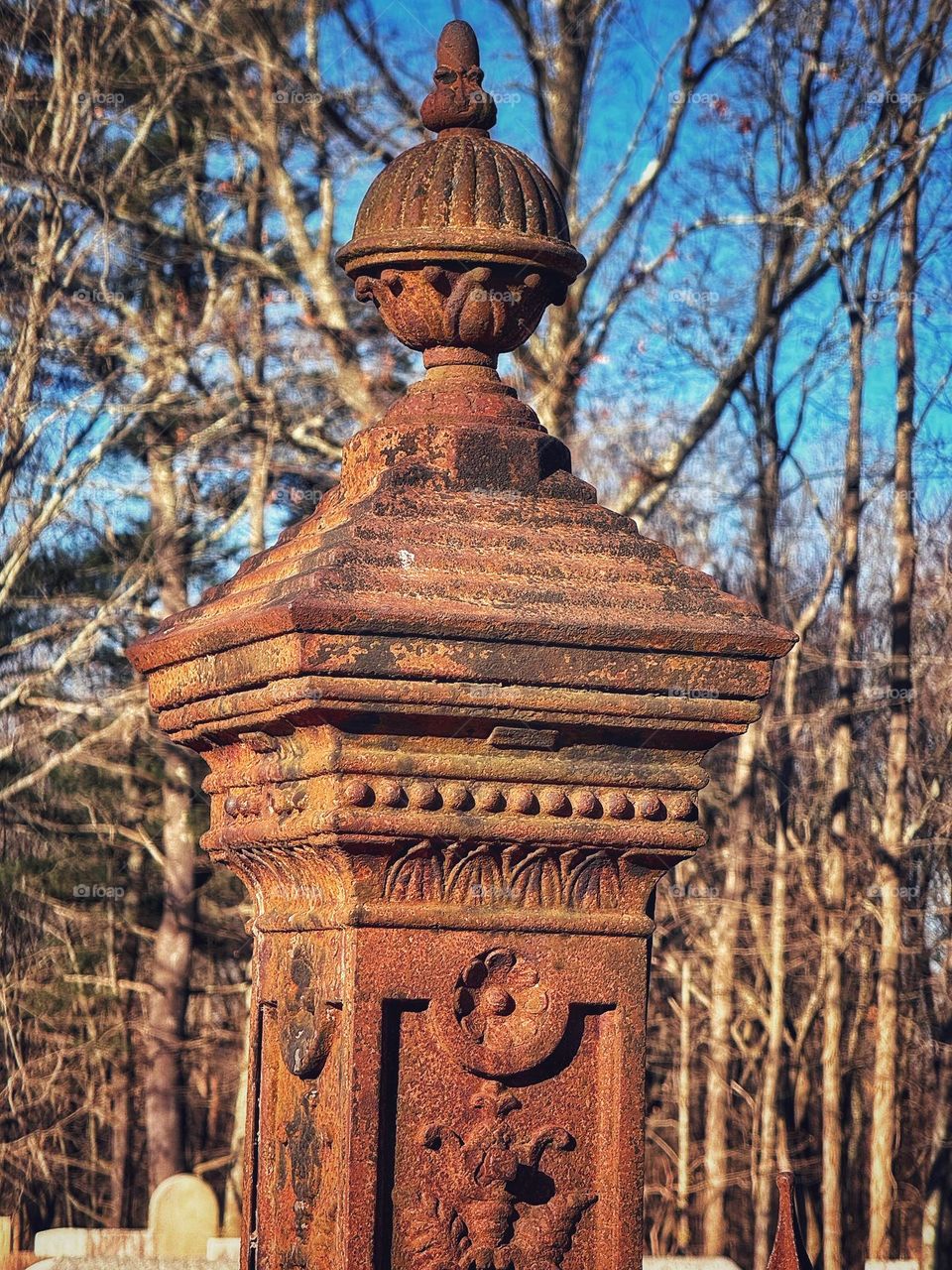 Rusted metal gatepost in a cemetery 