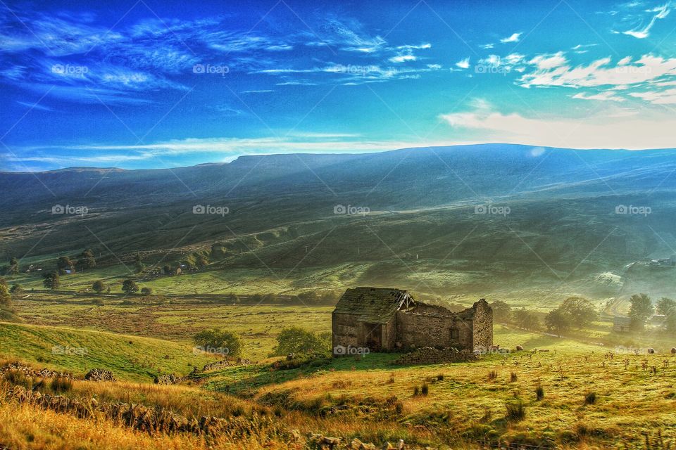 Disused Farm Barn. A bright morning over a deep farming valley with a disused barn that sheep are sleeping in.