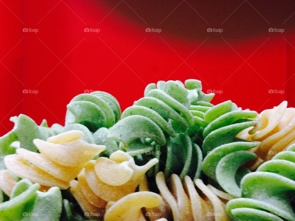 Close-up of coloured pasta against red background
