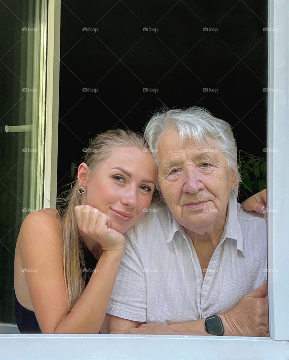 A young girl with her grandmother stand at the window