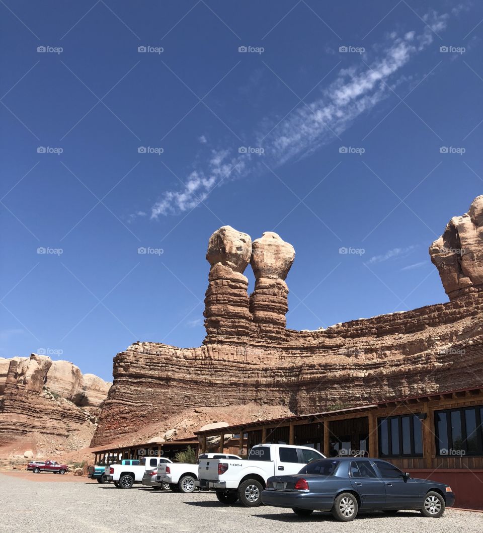 Outside outdoor natural rock formations at rest stop restaurant with building, cars, trucks in foreground and blue sky overhead