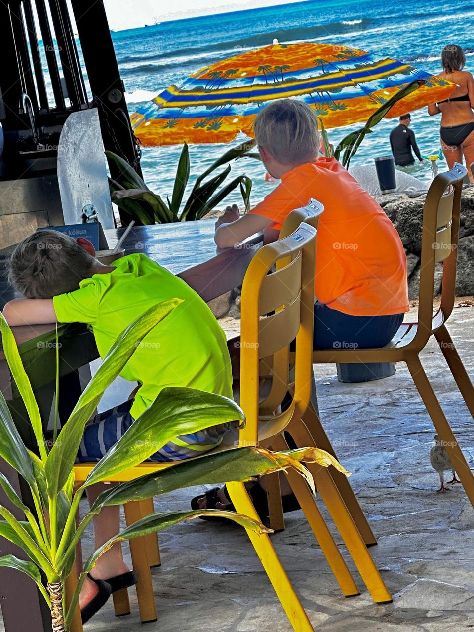 Two boys in bright T-shirts resting in a beach side cafe