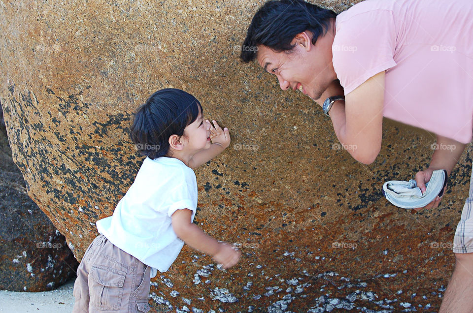 Portrait of father and son are smiling the background stones.