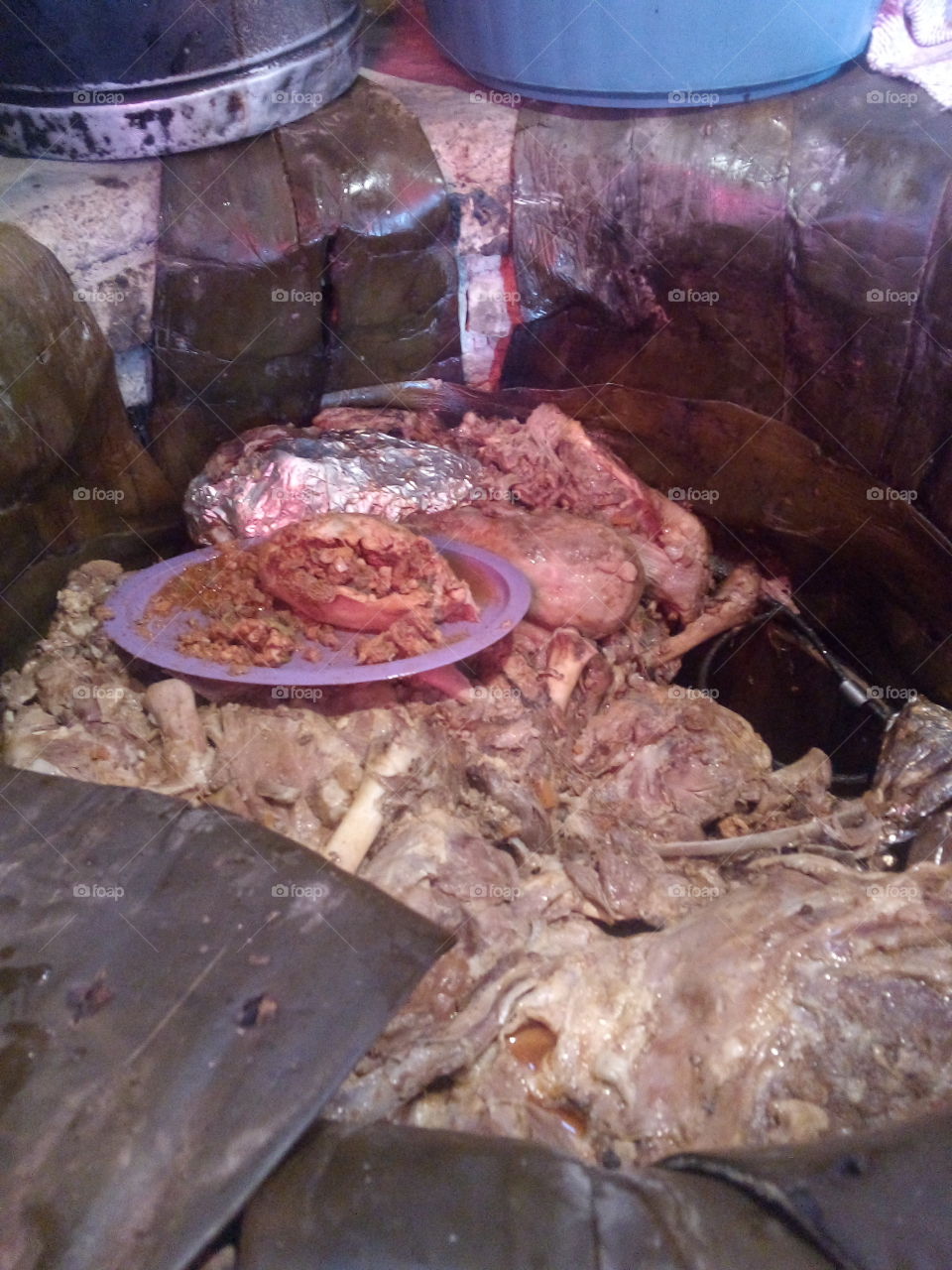 Barbacoa cocinandose en horno de piedra cubierta con pencas de maguey y horneada
