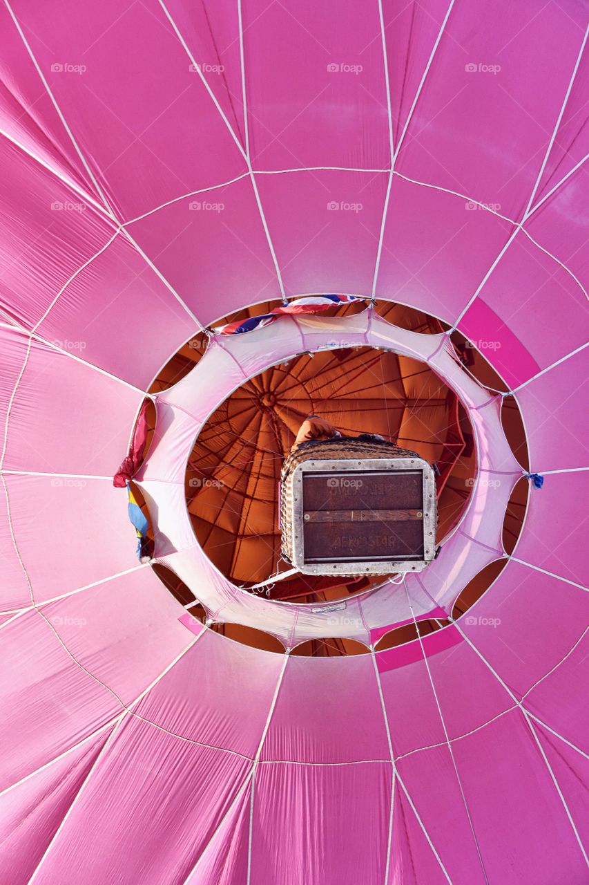 A hot air balloon festival in the winter creates a colorful scene. This is a pink balloon captured from below. Rich colors saturate.