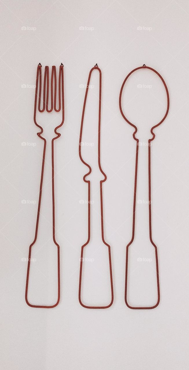 Beautiful wire wall decoration of cutlery - fork, knife and spoon, side view.