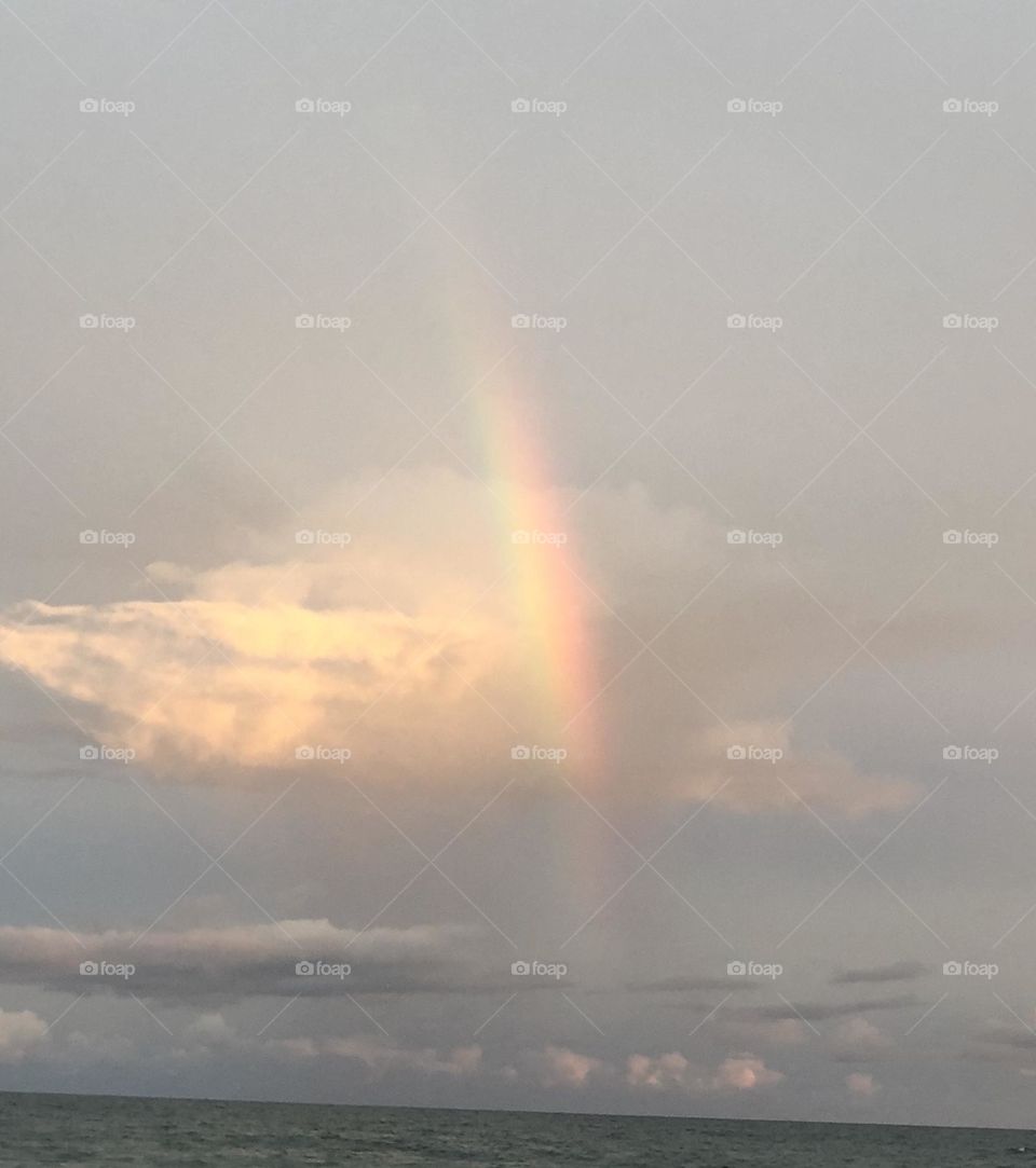 Rainbow and fluffy clouds over the ocean 