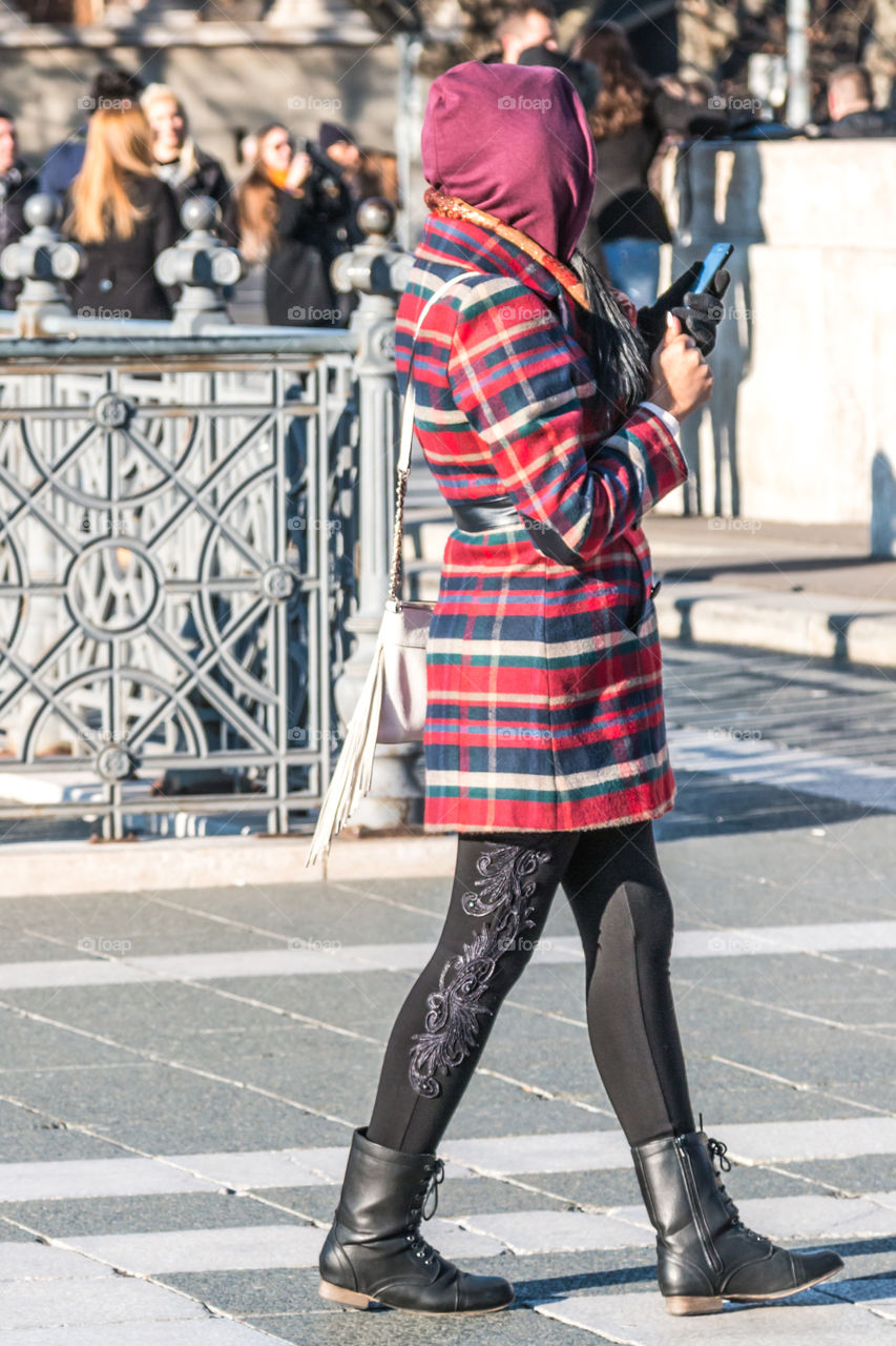 Young Woman Walking On The Street Sending A Text Message On Her Mobile Phone
