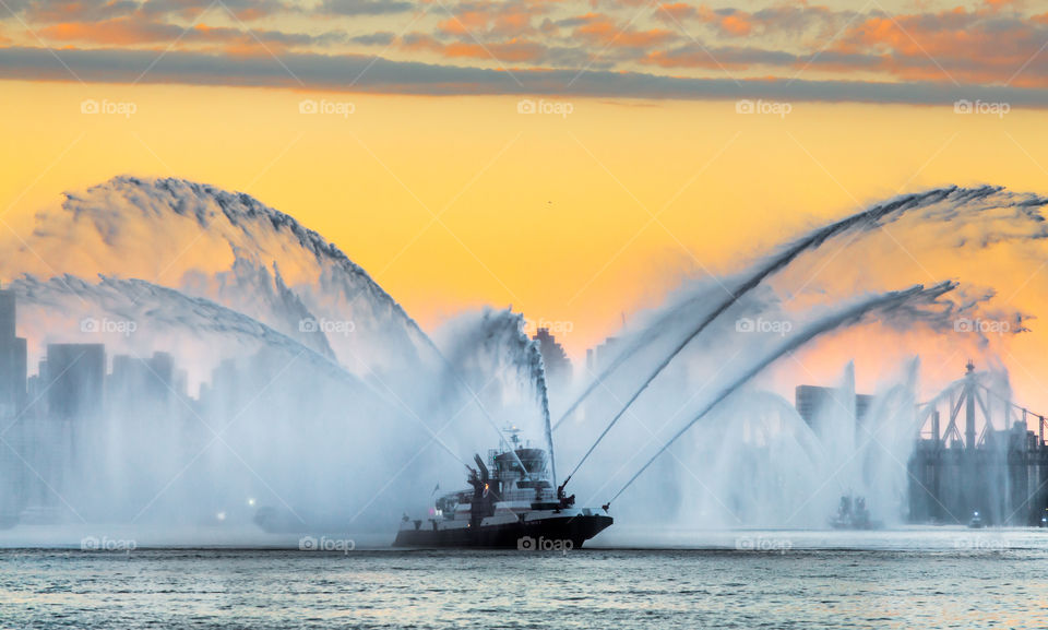 A boat shooting water during sunset prior to Macy's fireworks display.
