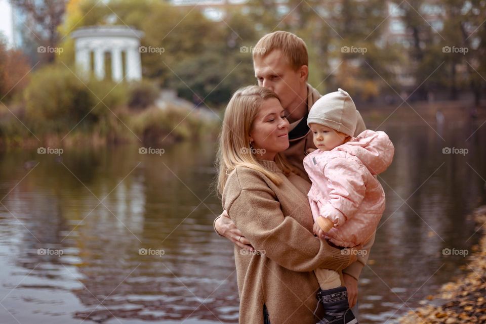 happy family on a walk in the autumn park near the lake