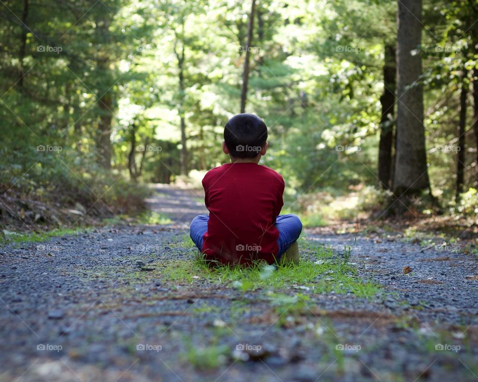 Young boy in red sitting on an hiking trail