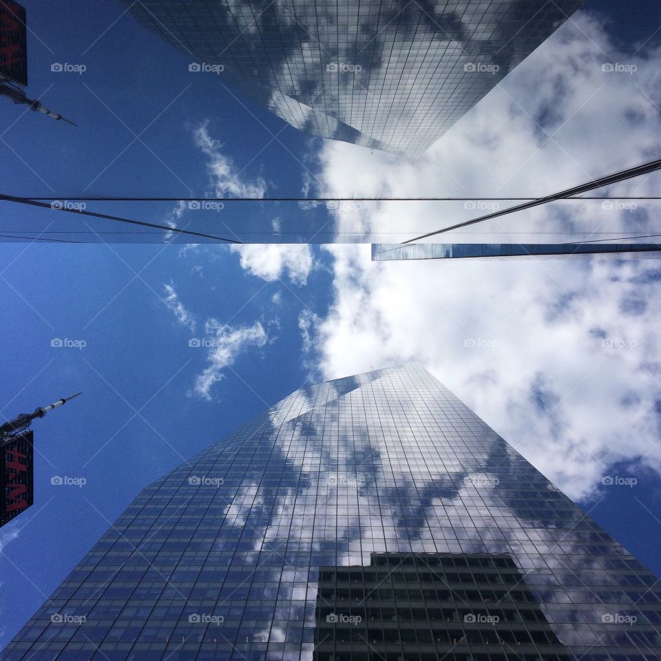 Looking up in Midtown Manhattan to the tall skyscrapers and cloudy blue sky 