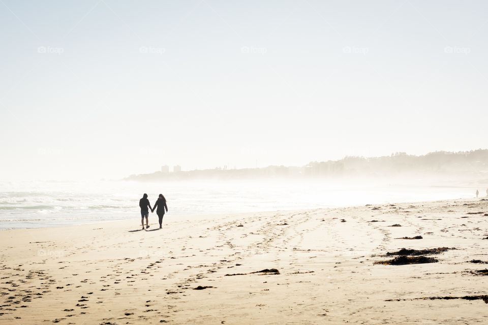 Picture of a beautiful couple taking a walk together at the beach in a heavenly day 