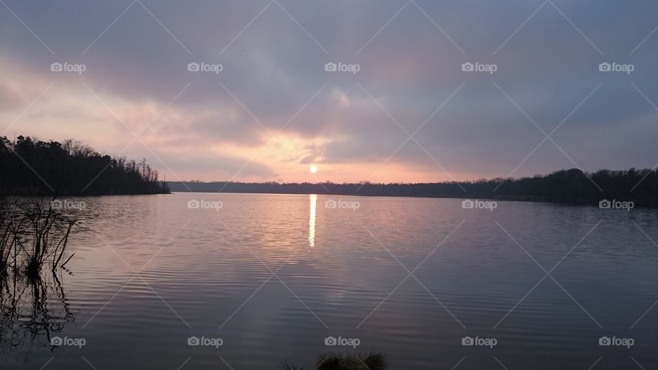 Sunset with reflecting sun and sky in the lake.