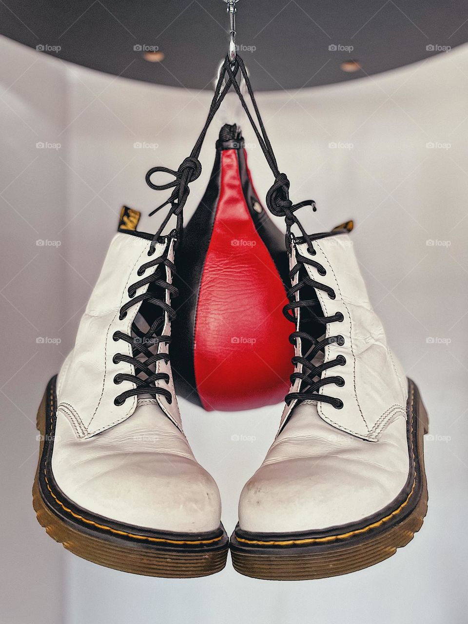 Classic white Doc Marten boots hanging from a speed bag, white boots with speed punching bag, Doc Marten white boots, classic style never goes out of style, boxing and boots, bright white boots 