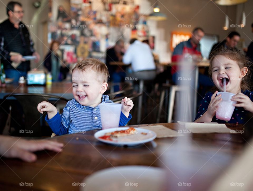Two little kids laughing at a restaurant 