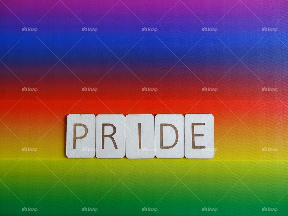 Wooden letters pride on rainbow background 