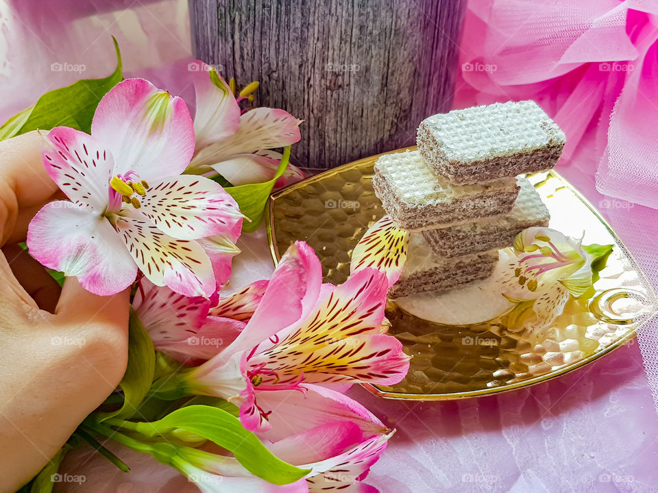 hazelnut milky cream wafer on a sugar covered golden plate decorated with flowers and petals