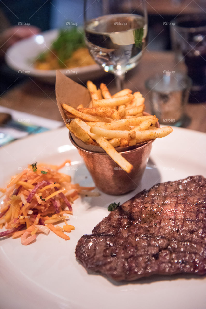 Main course at famous Jamie's Italian restaurant in London. The restaurant has it's name after world famous TV chef Jamie Oliver. Steak with fries and coleslaw.