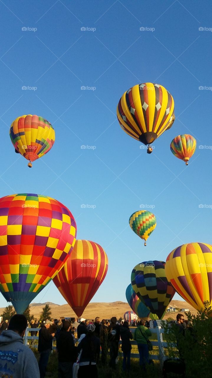 Bright colorful hot air balloons flying above a crowd of people