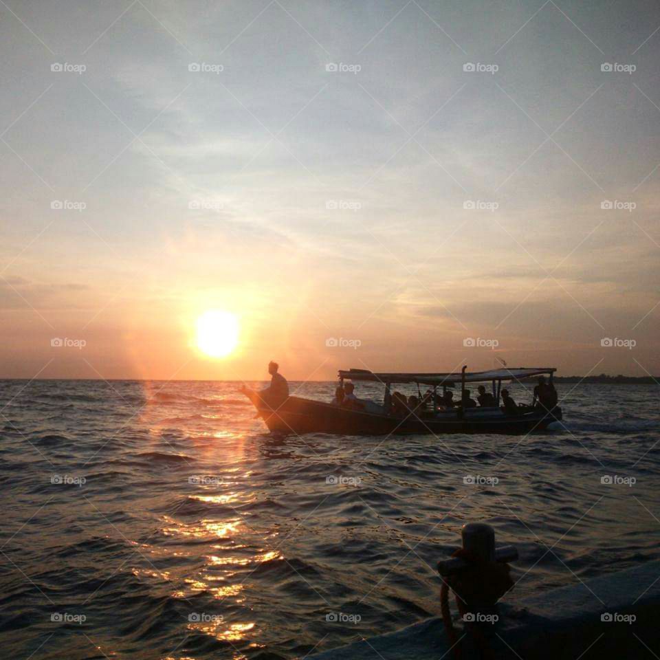 Boat sailing accompanied by sunset.
