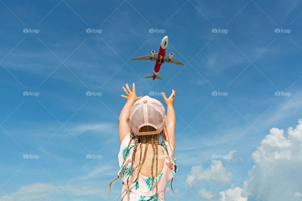 Little girl with blonde hair braids and aircraft in sky