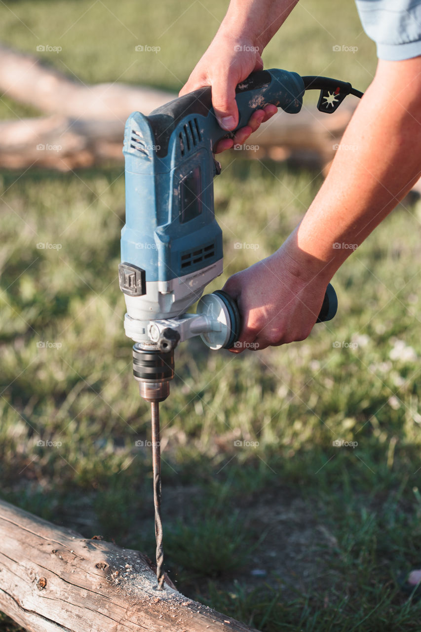 Man drilling hole in timber while working in garden. Real people, authentic situations