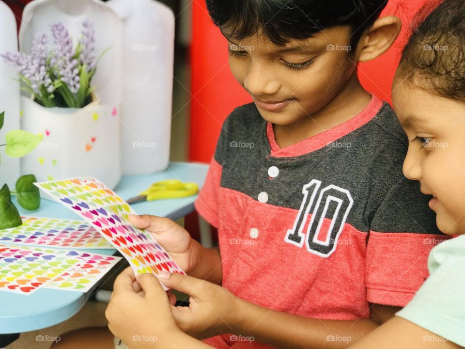 Kids doing craft and turning plastic milk bottles into flower pots.