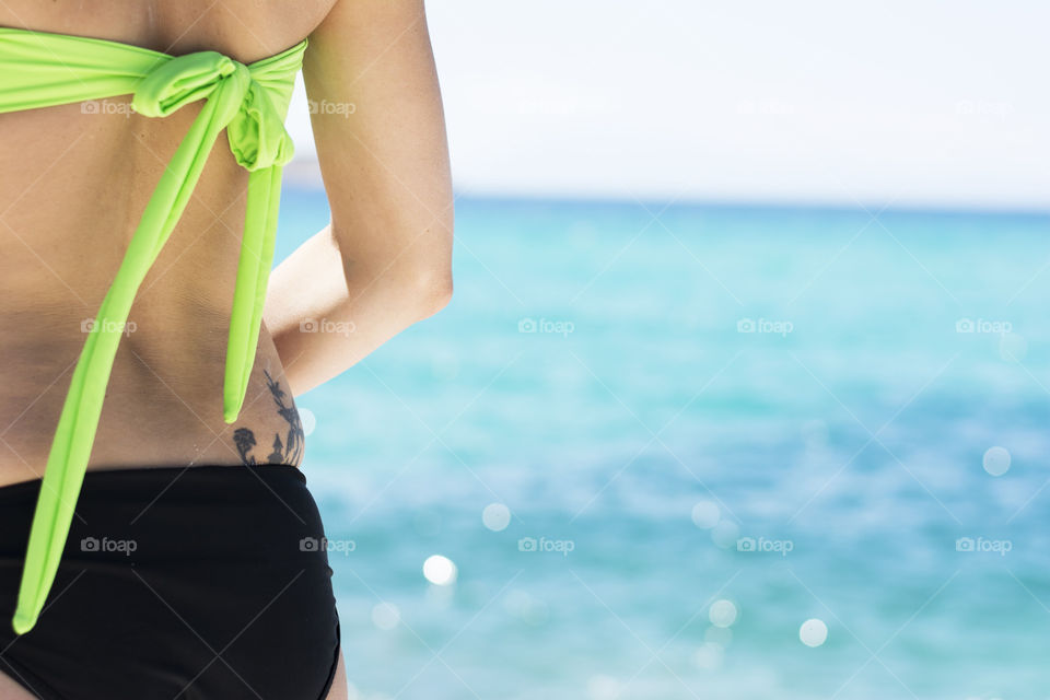 woman on beach. woman in neon bikini with tatoo on the beach