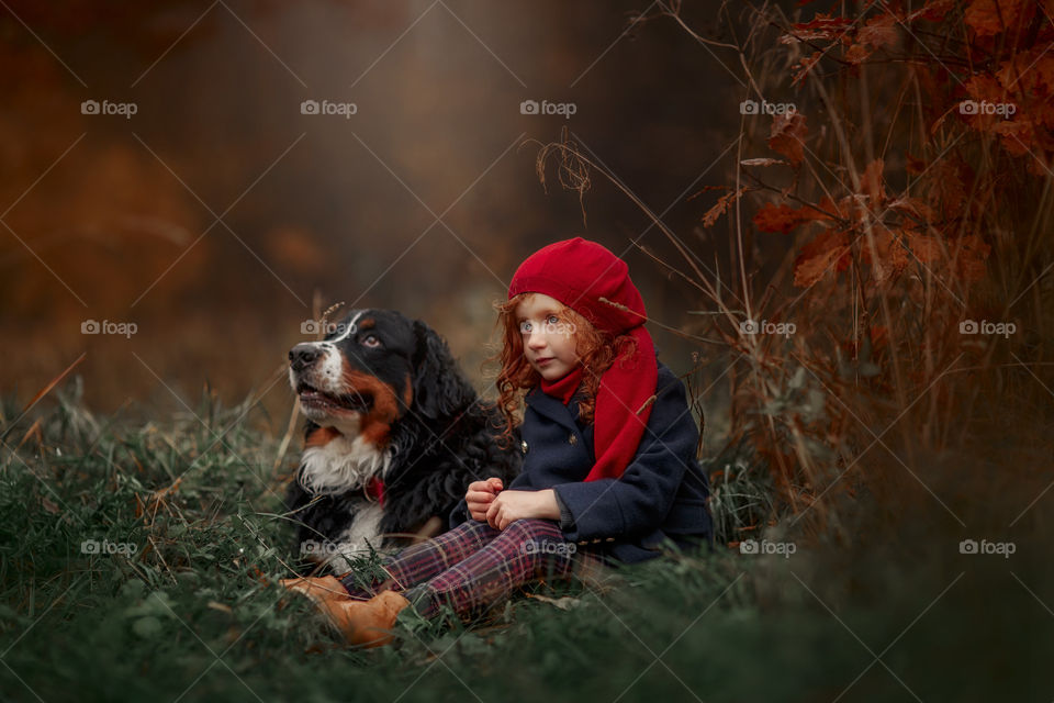 Little girl with dog in autumn park 