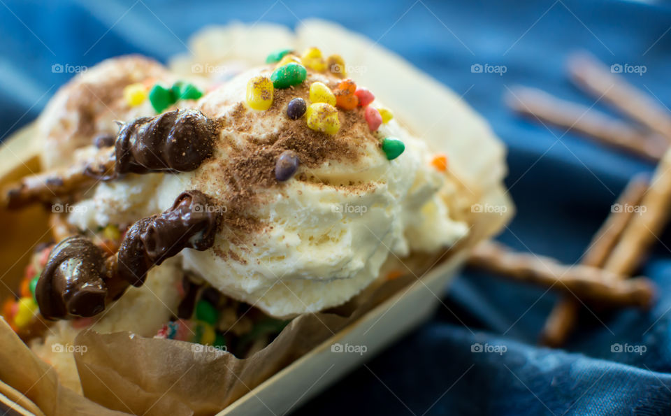 Rich Chocolate covered pretzels on vanilla ice cream scoops covered in cocoa sugar and spice with rainbow colored sprinkles sweet and salty dessert on table with stick pretzels in background gourmet dessert photography 