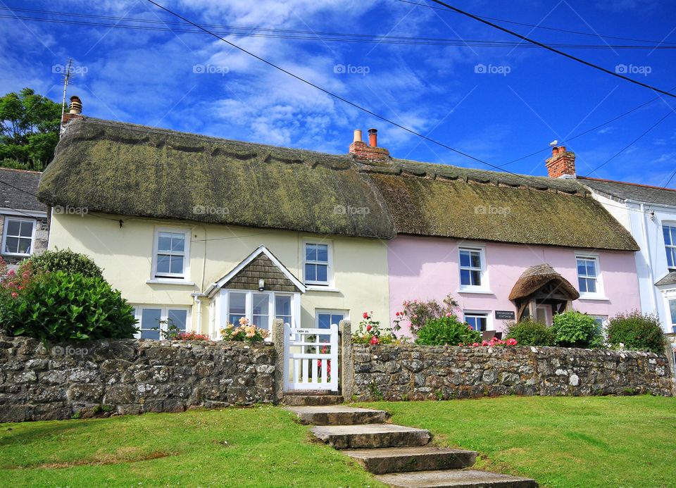 A pair of brightly painted, thatched cottages in a Cornish fishing village called Coverack.