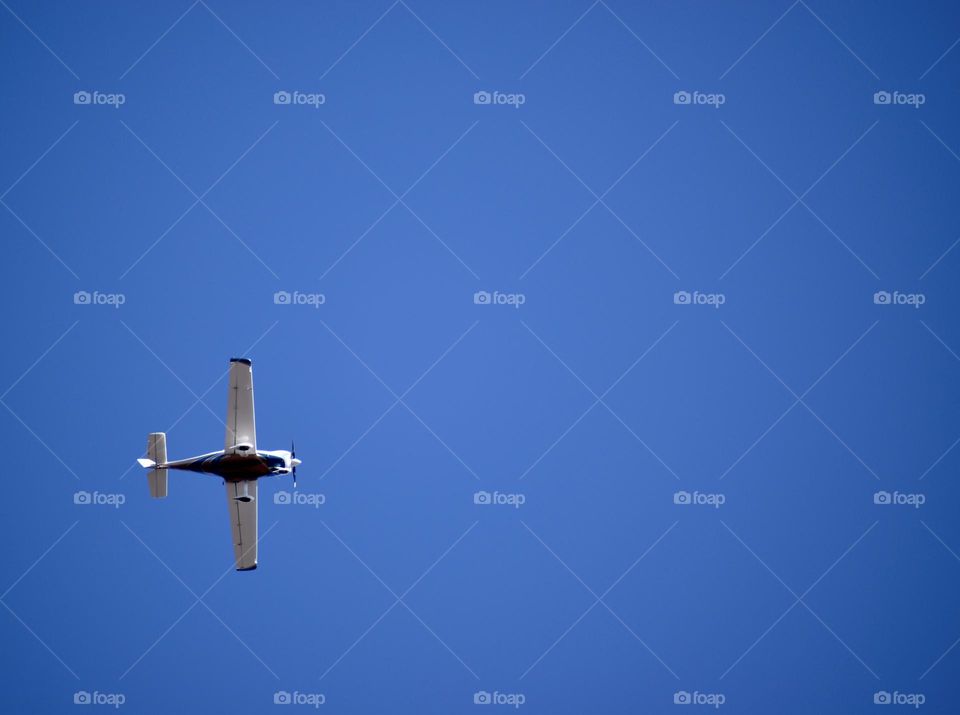 A plane flies through the blue sky