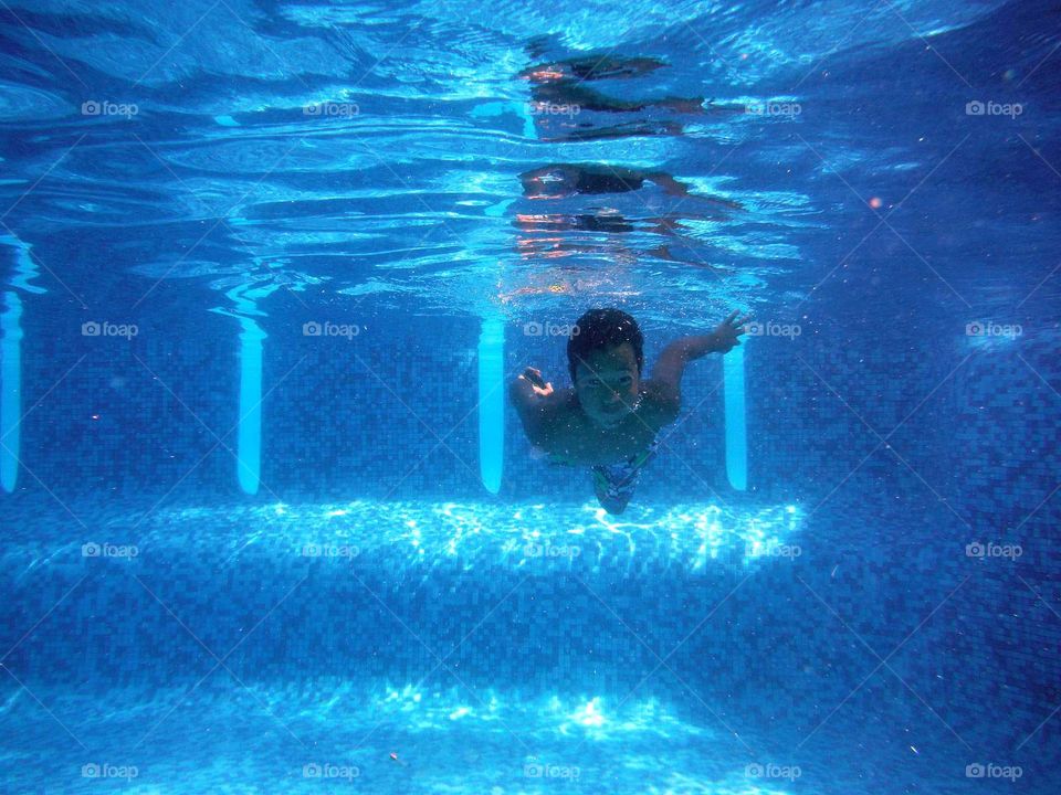 Boy swimming under water in the pool