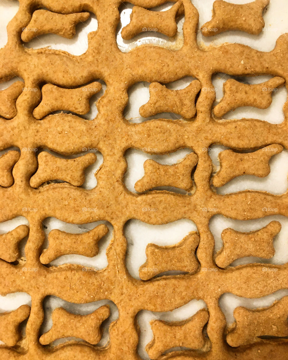 Homemade dog treats shaped like bones cut in whole wheat dough ready to be baked for all the good and perfect puppies in the world. 