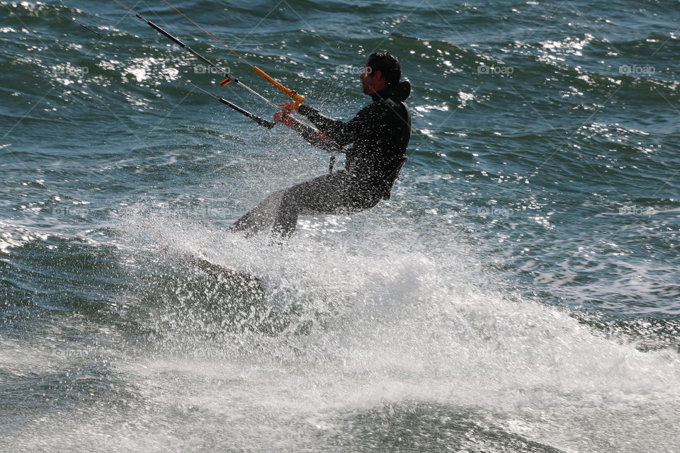 Kite surfer splashing water while riding the waves